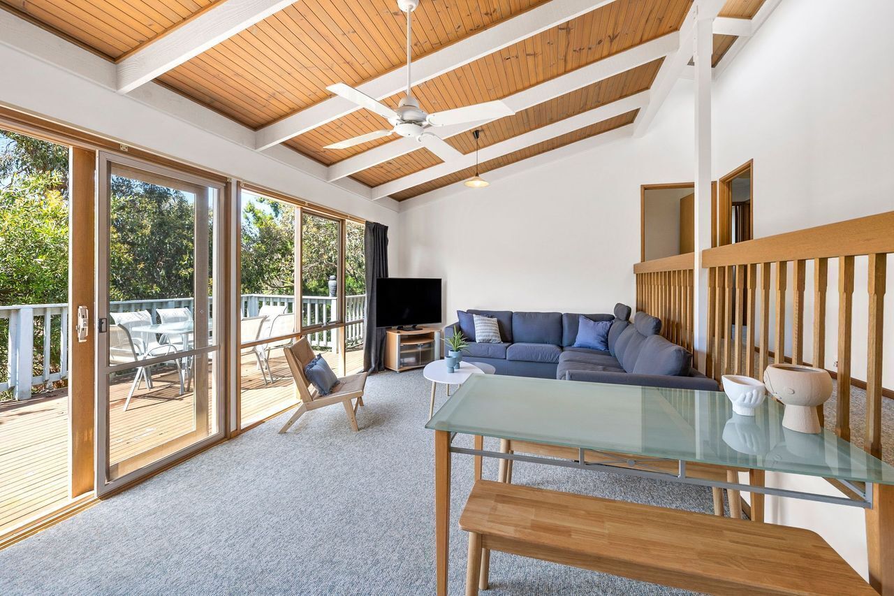 A spacious living area with a glass table, a sofa, and a television.