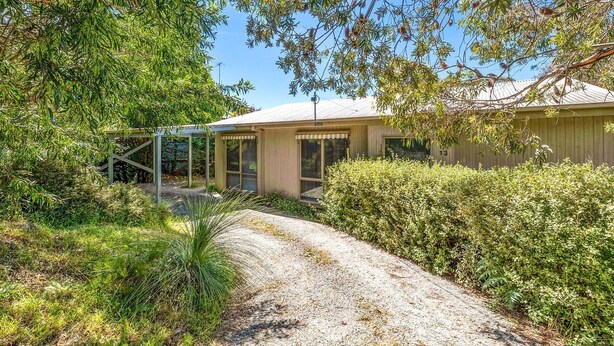 A house with a gravel driveway, surrounded by dense greenery and trees. - Oasis on Weir (Anglesea)