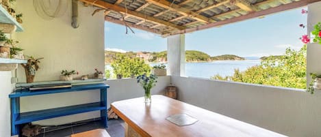 Terraza costera con una mesa de madera, un banco azul y plantas en macetas.