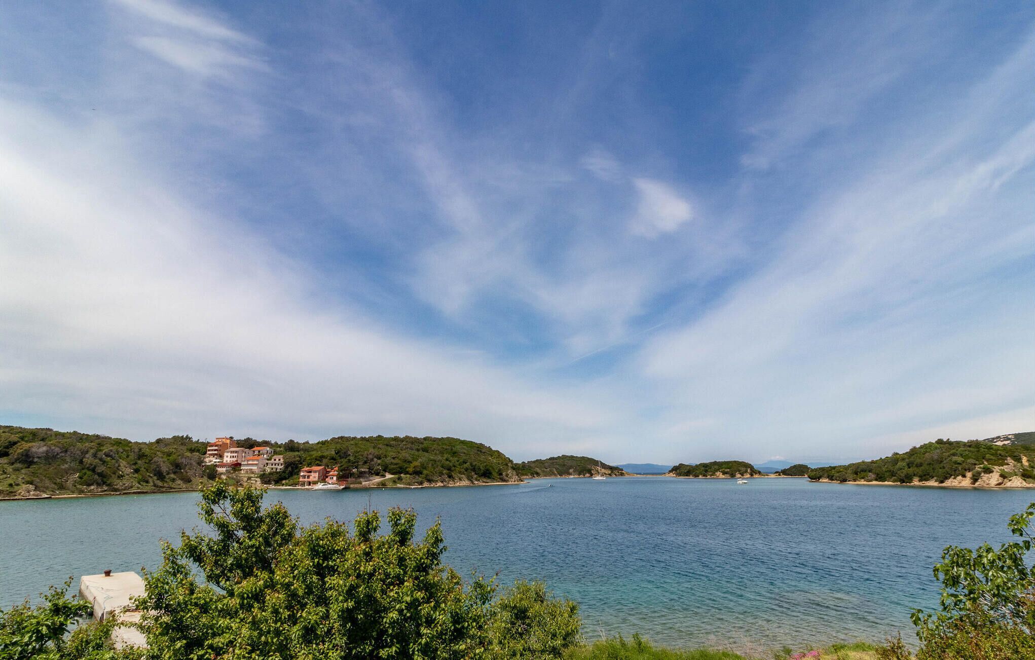 Un paysage côtier avec un ciel dégagé, une mer calme et des bâtiments situés sur la côte.
