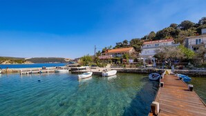 Una marina costera con aguas azules cristalinas, muelles de madera y varios barcos.