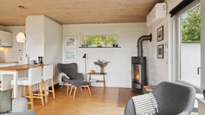 A modern living room with a fireplace, wooden flooring, and a dining area with a wooden table and chairs. - Lovely home in Samsø with WiFi (Samsø)