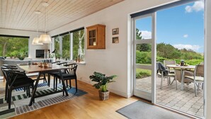 A modern kitchen with large windows, a dining area with chairs, and a view of the outdoors. - Lovely home in Samsø with WiFi (Samsø)