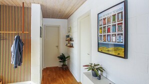 A hallway with wooden flooring, a door, a shelf with books and a plant, and a framed picture on the wall. - Lovely home in Samsø with WiFi (Samsø)
