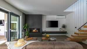 A modern living room with a large sofa, a fireplace, a flat-screen TV, and a staircase. - Gorgeous home in Nedescina with sauna (Nedescina)