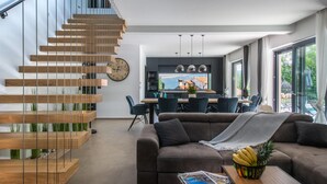 A modern living room with a staircase, a dining area, and a kitchen. - Gorgeous home in Nedescina with sauna (Nedescina)