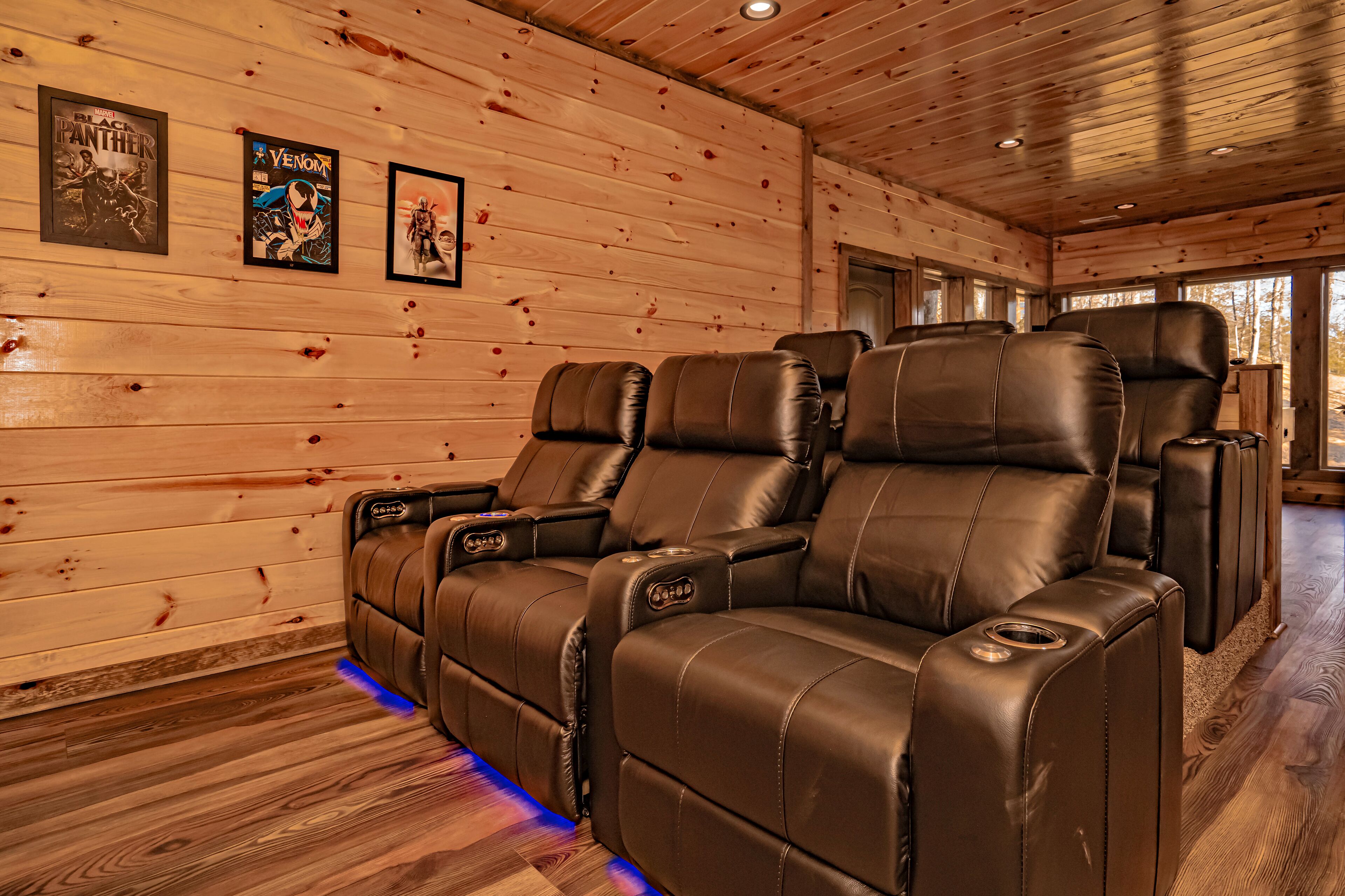 A wooden interior with leather recliners and framed posters on the wall.