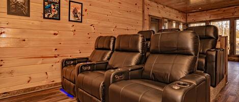 A wooden interior with leather recliners and framed posters on the wall.