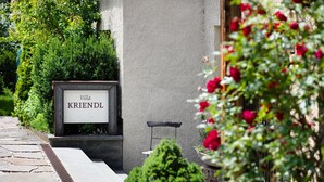 Un letrero con 'Villa KRIENDL' en la fachada de un edificio, rodeado de follaje y un camino de piedra.