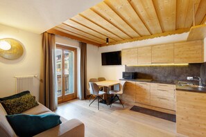 A modern kitchen with wooden cabinets, a dining area with a table and chairs, and a built-in TV.