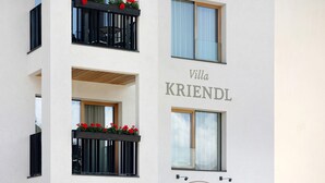 Un edificio de varios pisos con balcones, un letrero que dice 'Villa KRIENDL' y el logotipo de 'Prodevilla Spa Textiles'.
