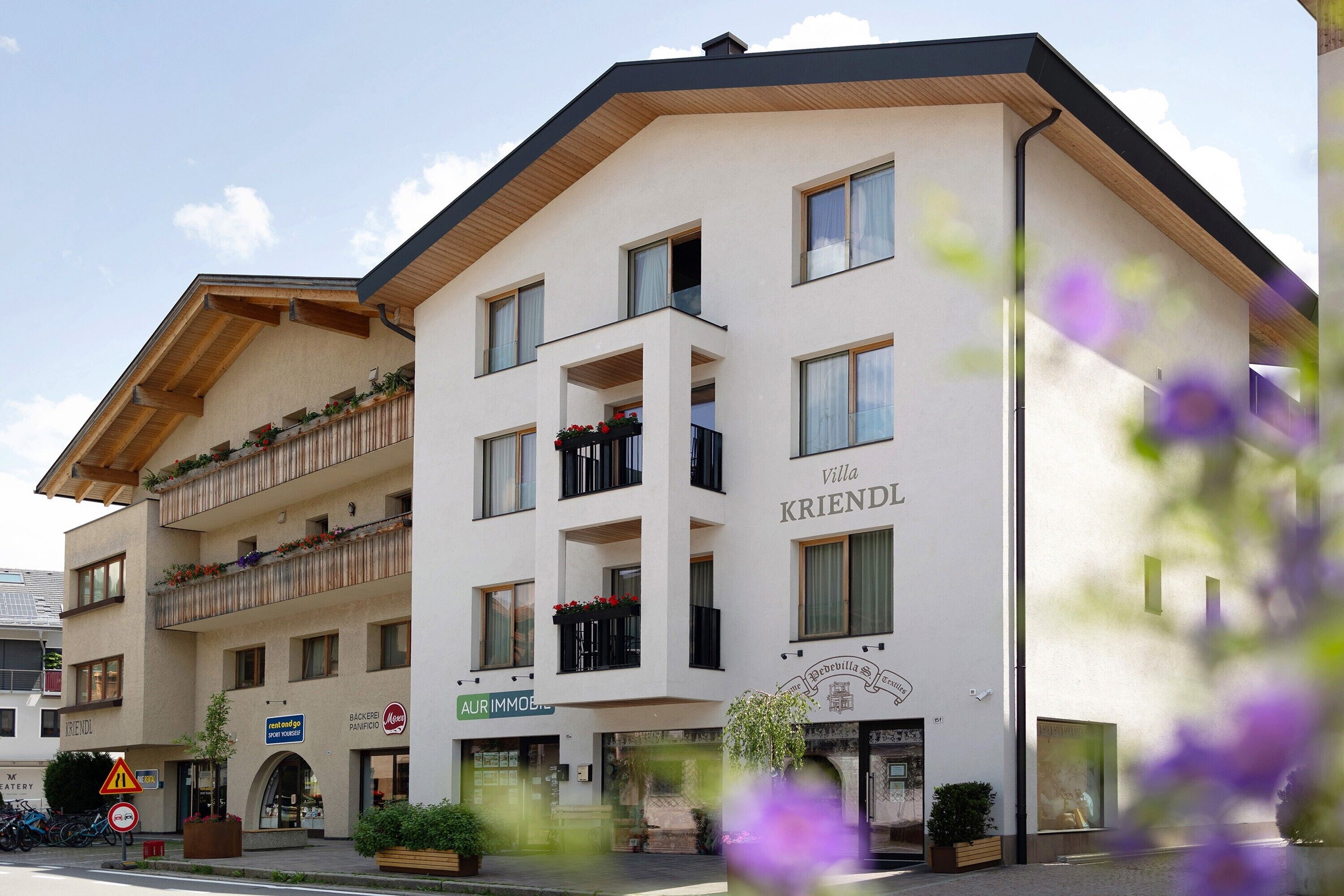 A multi-story hotel with balconies, a sign reading 'Villa KRIENDL,' and a street sign for 'AUR IMMOBILIER.'