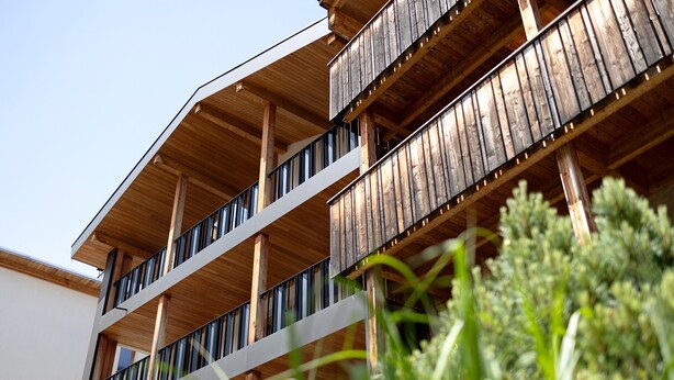 Een meerlaags gebouw met balkons en houten balken.