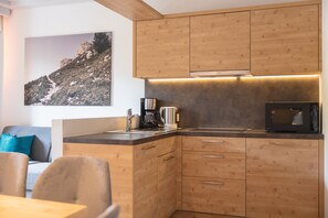 A modern kitchen with wooden cabinets, a coffee maker, and a microwave.