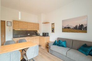 A compact living space with a kitchenette, a dining area, and a sofa with cushions. - Apartment 'Kriendl Nr 4' with Mountain View, Private Terrace and Wi-Fi (Valdaora di Mezzo)