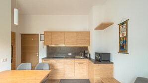 Une cuisine compacte dotée de meubles en bois, d’un four à micro-ondes encastré et d’un petit coin repas avec une table et des chaises.