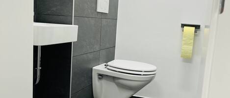 Ein modernes Badezimmer mit Toilette, Waschbecken und Handtuchspender.