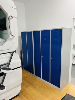 A locker room with blue lockers, a white bench, and a white sink. - Space Home Apartment - Prater (Vienna)