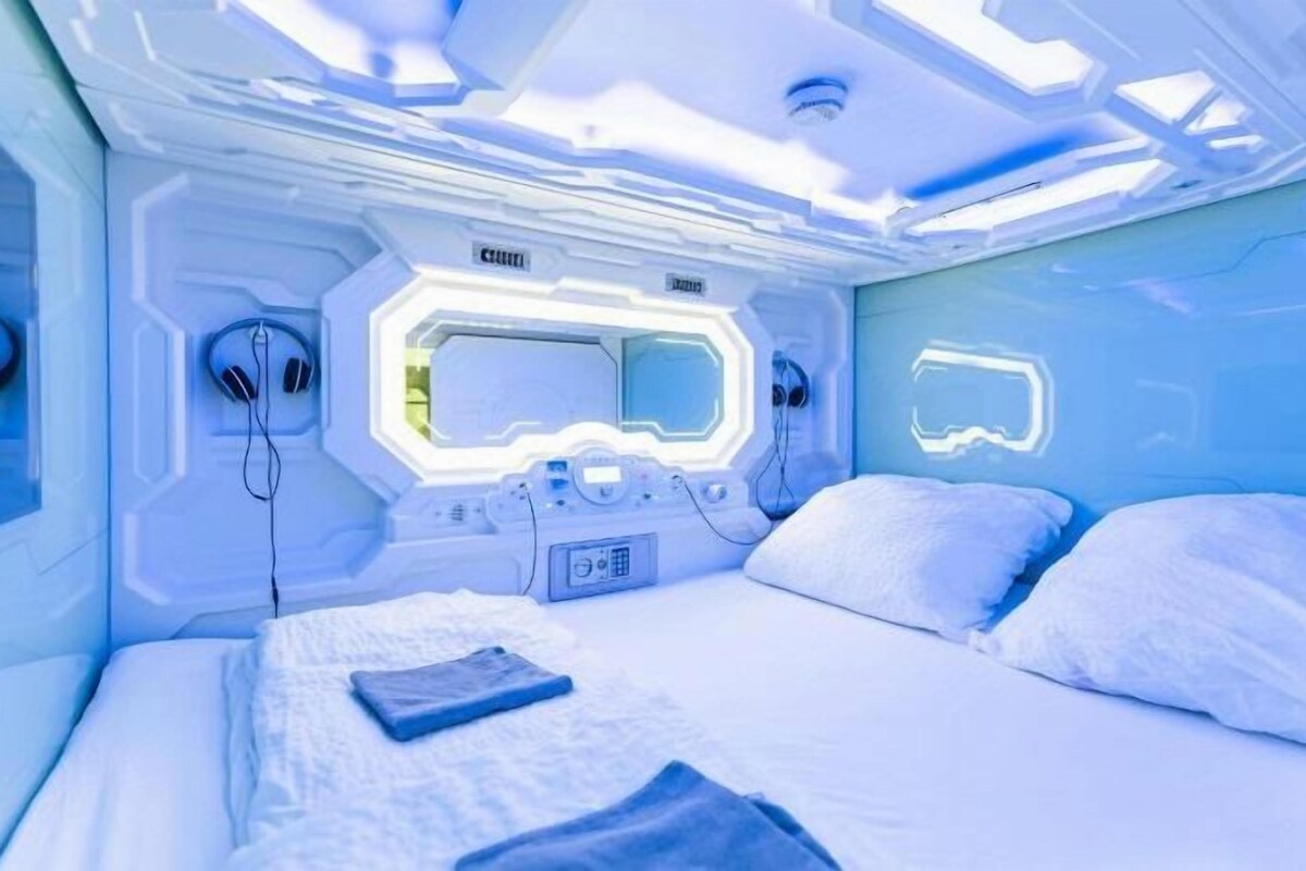 Una habitación con una cama, una mesita de noche y un panel de control con botones y una pantalla.