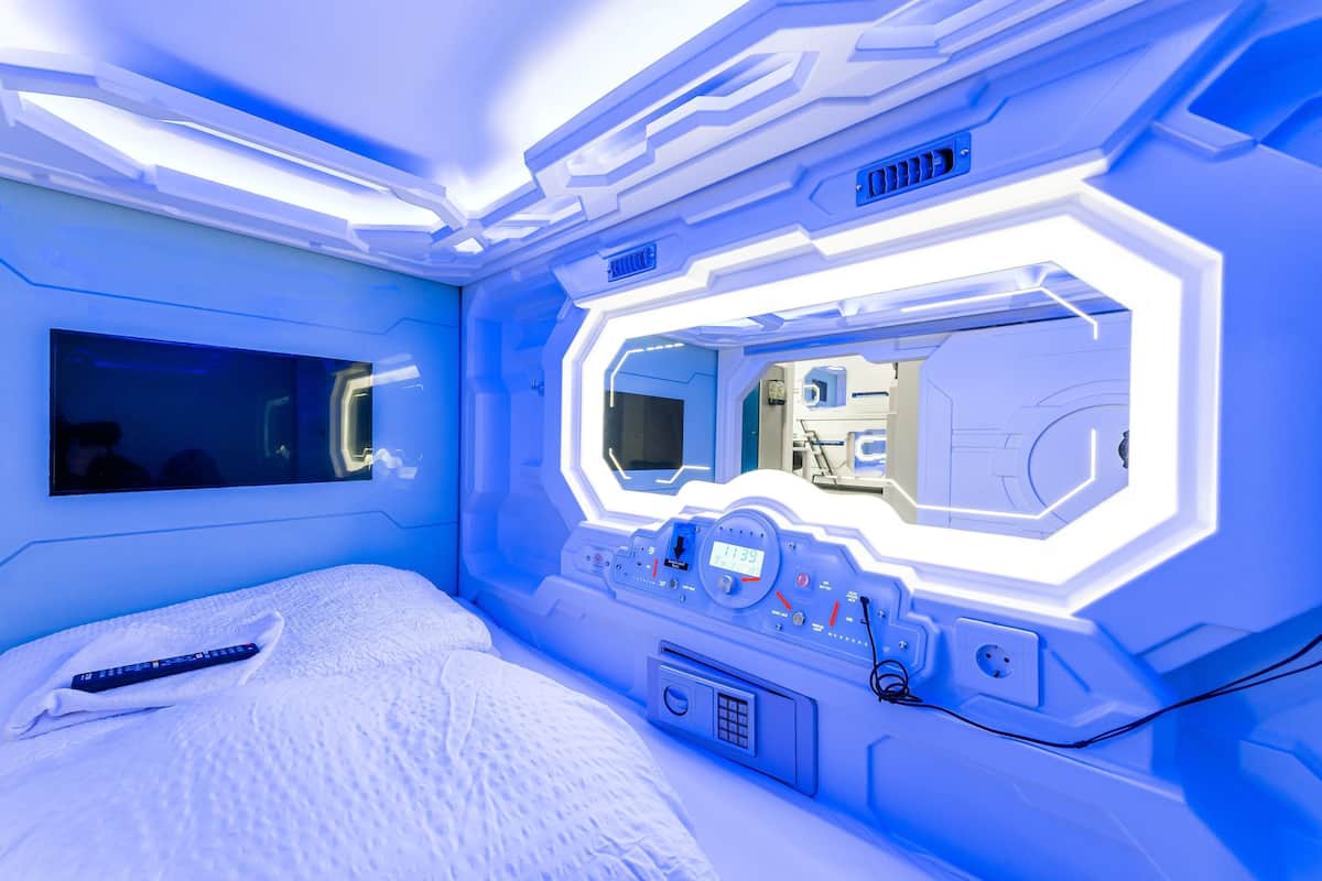 A room with a bed, a control panel, and a large mirror.