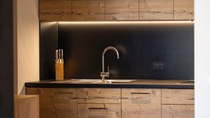 Eine moderne Küche mit Spüle aus Edelstahl, Holzschränken und einer eleganten schwarzen Arbeitsplatte.