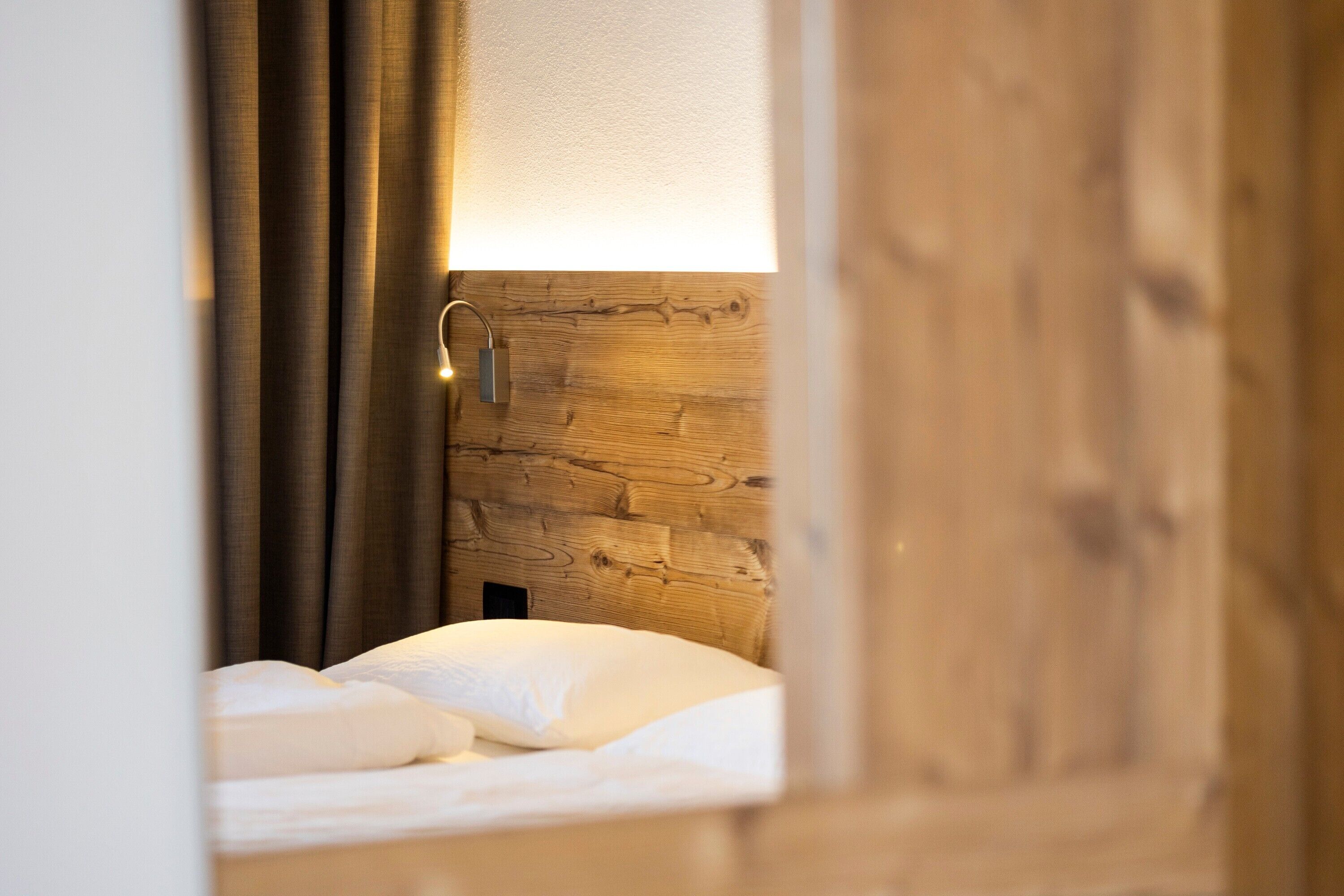 Ein Schlafzimmer mit einem Holzkopfteil, einem Bett mit weißer Bettwäsche und einem Nachttisch.