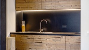 Eine moderne Küche mit Spüle aus Edelstahl, Holzschränken und einer eleganten schwarzen Arbeitsplatte.