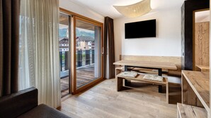 Ein modernes Zimmer mit Holzboden, einer Couch, einem Tisch und einem an der Wand befestigten Fernseher.