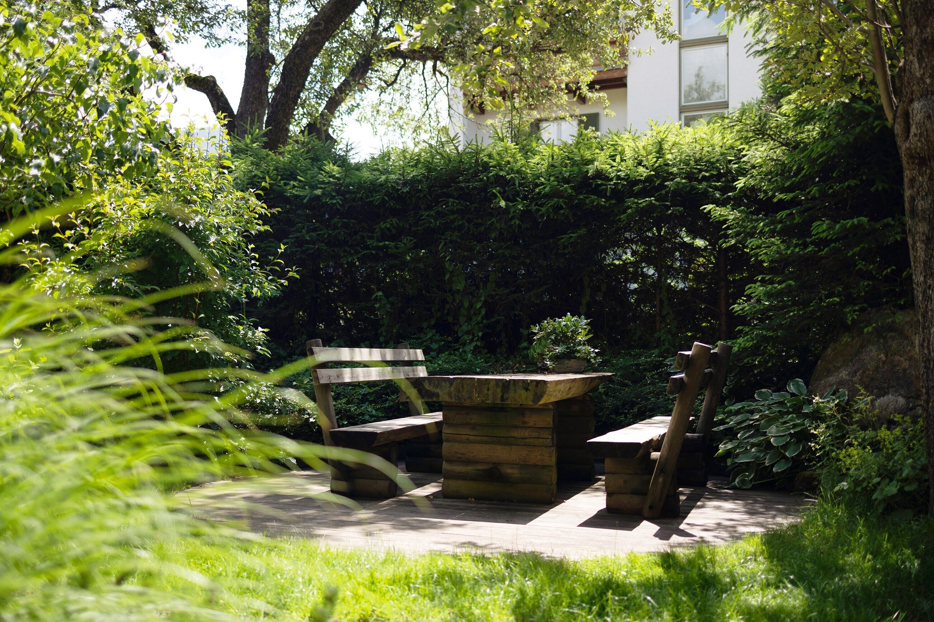 A garden with a wooden bench, a stone table, and a stone bench.