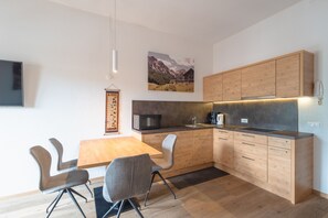 Une cuisine moderne avec des meubles en bois, une table à manger avec des chaises, un four à micro-ondes et une machine à café.