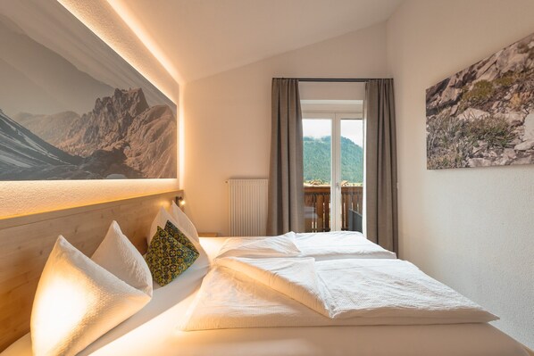 Une chambre d’hôtel avec un lit, une vue sur les montagnes, un tableau au mur et une fenêtre avec des rideaux.