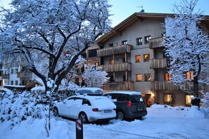 A multi-story building with balconies, parked cars, and snow-covered trees. - Apartment 'Kriendl Nr 3' with Mountain View, Shared Garden and Wi-Fi (Valdaora di Mezzo)