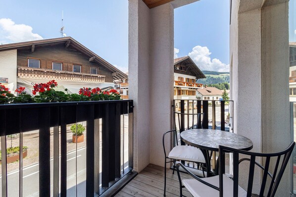 Un balcon avec une table et des chaises, une vue sur les bâtiments et un ciel dégagé.