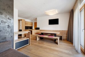 Un salon moderne avec un banc en bois, un téléviseur à écran plat et une grande fenêtre agrémentée de rideaux.