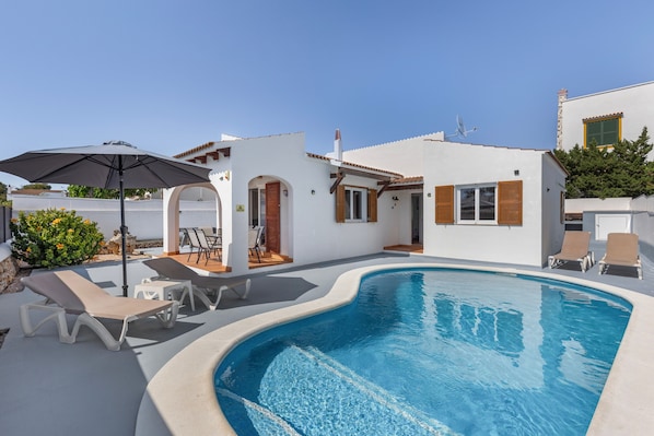 A modern pool area with lounge chairs and a pergola.