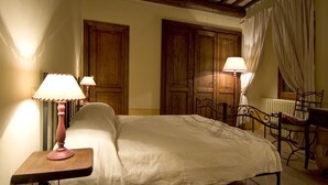 A bedroom with a bed, two bedside lamps, a wooden chair, and a window with curtains. - Benozzo vacation apartment with garden and pool (Montefalco)