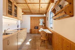 Une cuisine avec des meubles de rangement en bois, un évier et un coin repas comprenant une table et des chaises.