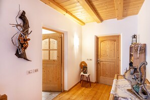 A wooden interior with a rustic decor, including a wall-mounted sculpture, a wooden door, and a small table with a lantern.