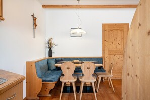 A wooden dining area with a bench and chairs, a hanging light fixture, and a wooden door.