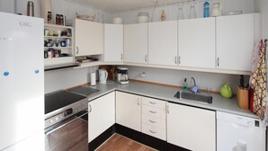 A compact kitchen with white cabinets, a Bosch refrigerator, a coffee maker, and a dishwasher.