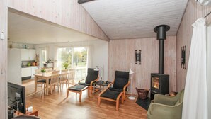 A cozy living room with a fireplace, wooden flooring, and a dining area with a table and chairs.