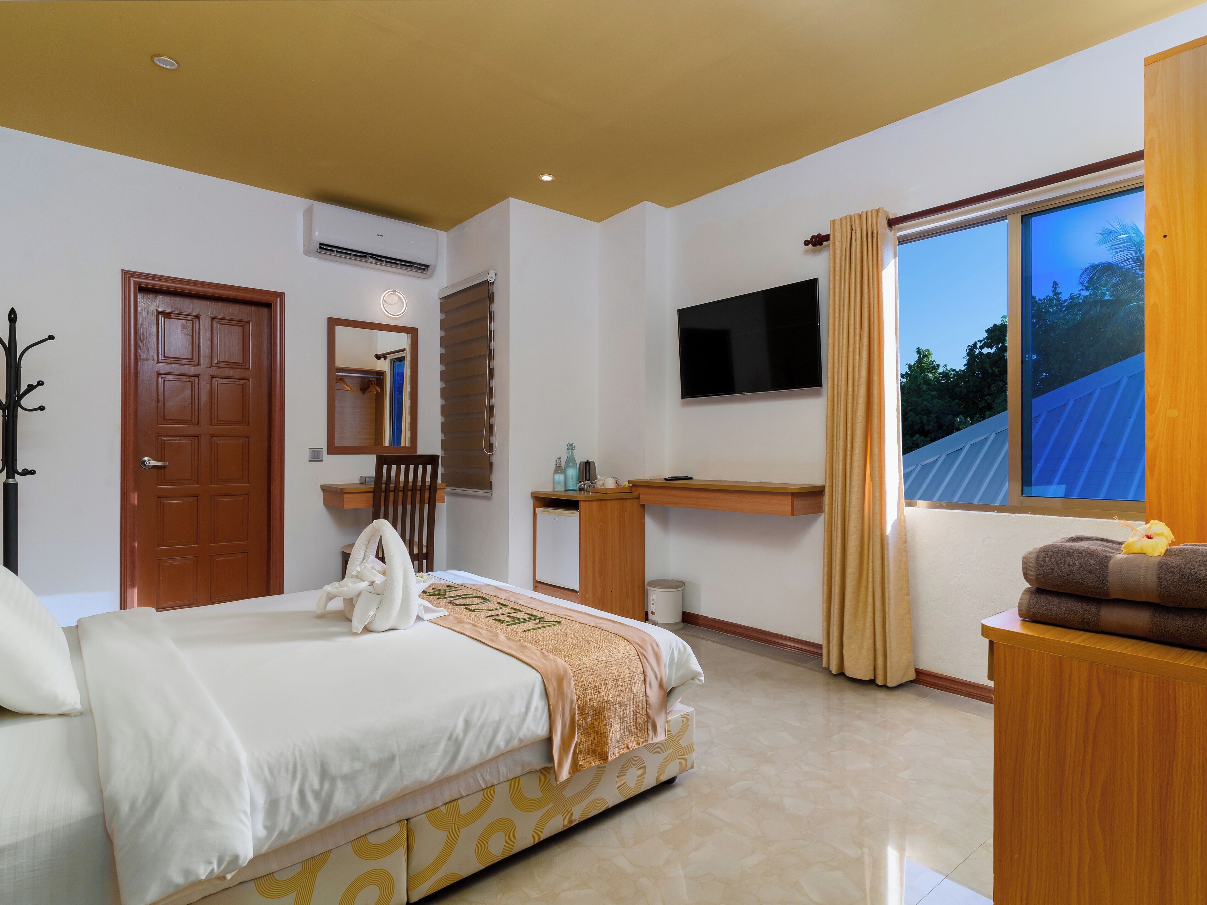 A hotel room with a bed, a desk, a television, and a window with a view.