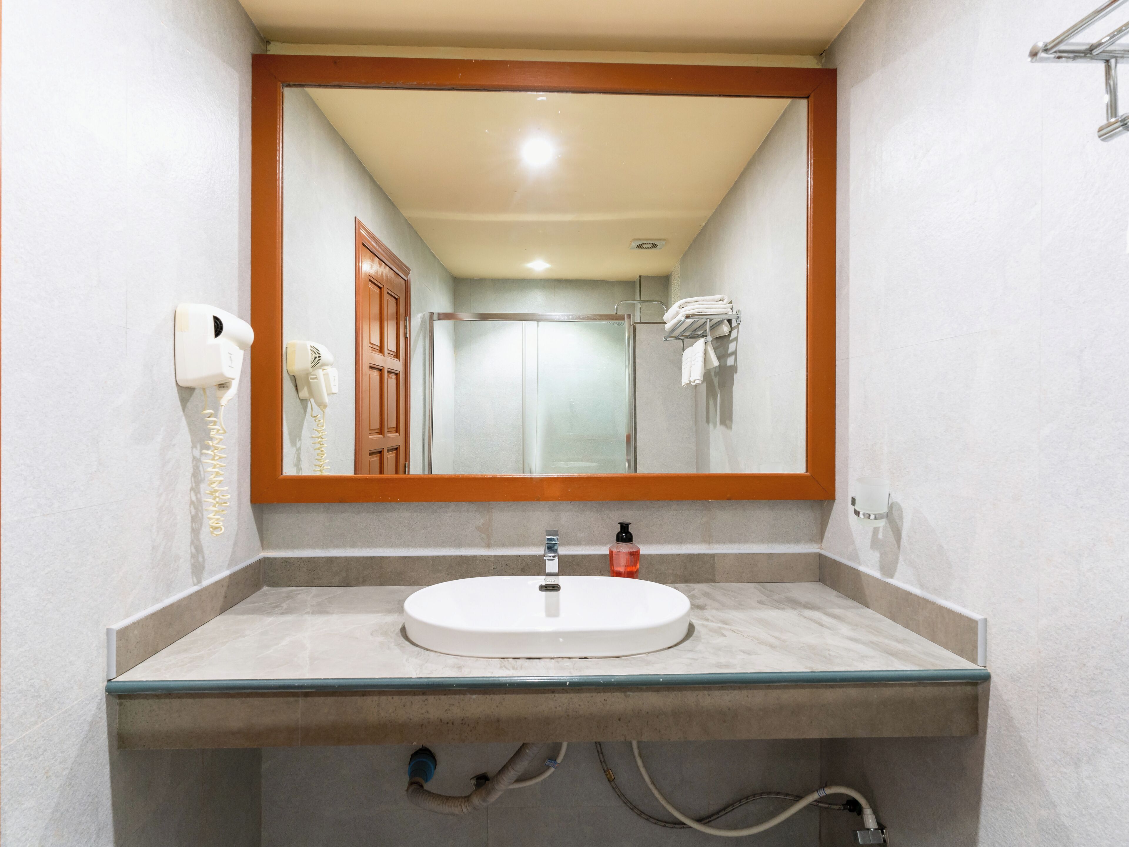Un baño con lavamanos de cristal, un secador de pelo y un tendedero para toallas.