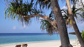 Am Strand, weißer Sandstrand, Liegestühle, Sonnenschirme