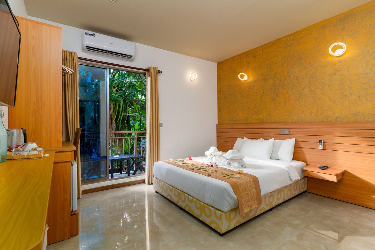 Una habitación de hotel con cama, escritorio, teléfono y ventana con cortinas.