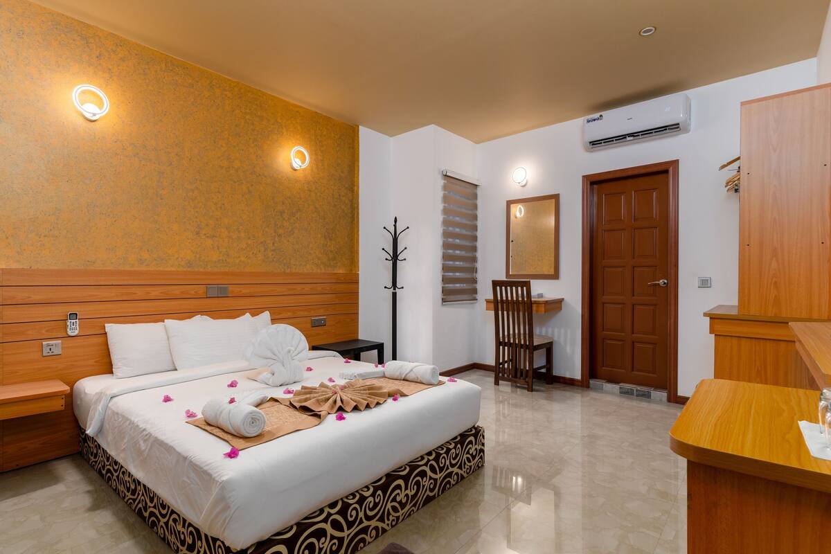 Una habitación de hotel con una cama grande, un cabecero de madera, un escritorio y un espejo.