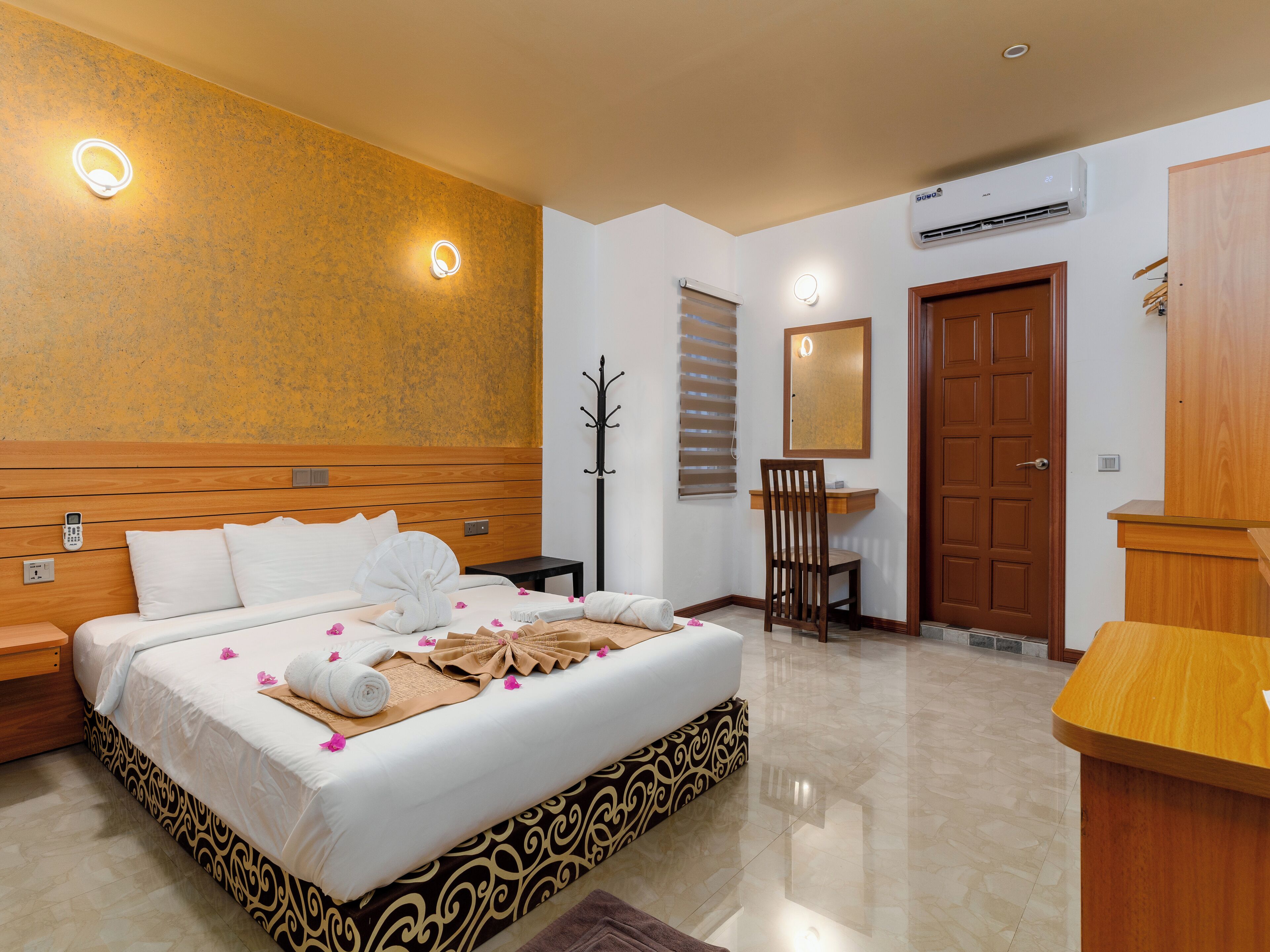 A hotel room with a bed, bedside table, chair, and a desk.