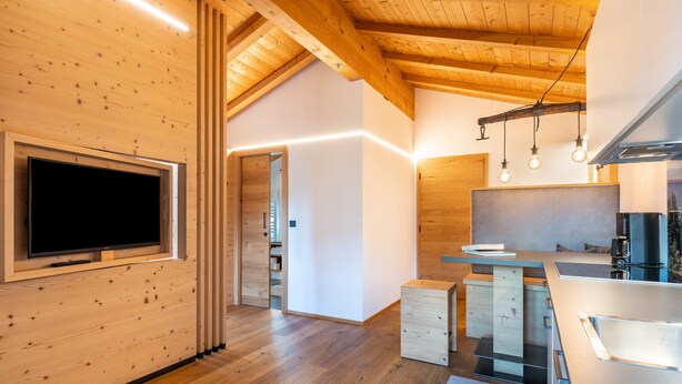 Eine moderne Küche mit Holzbalken, integriertem Fernseher und Pendelleuchten.