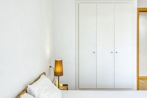Une chambre à coucher avec un lit, une table de chevet avec une lampe et une armoire blanche.