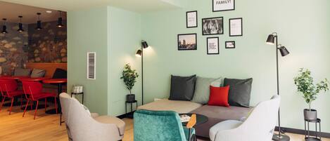 A modern living room with a sofa, two armchairs, a coffee table, and a dining area with red chairs and a table.